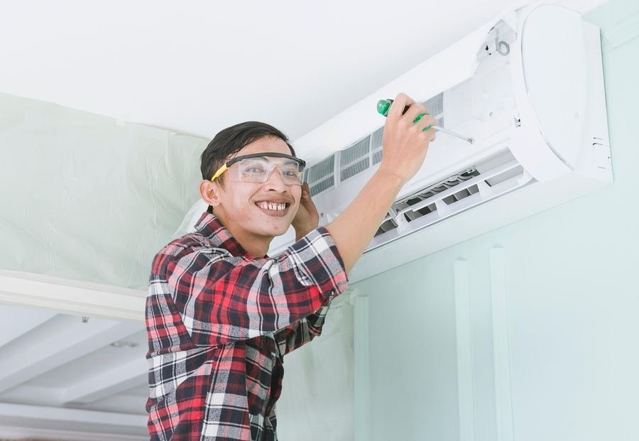 HVAC technician repairing a wall-mounted air conditioning unit